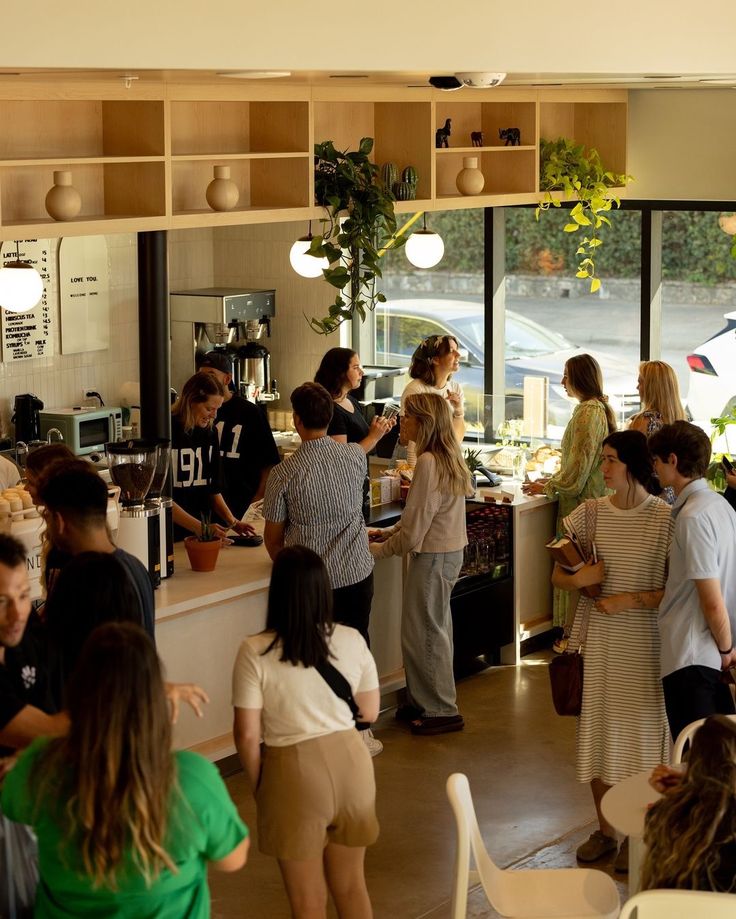 a group of people standing around in a room next to a counter with food on it