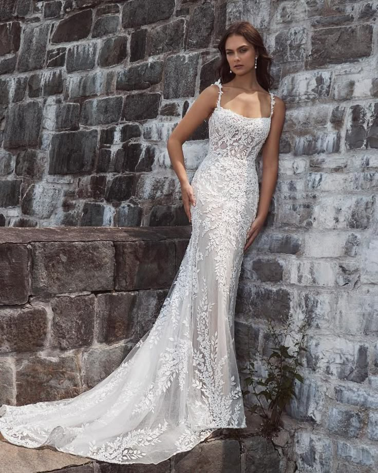 a woman in a wedding dress leaning against a brick wall