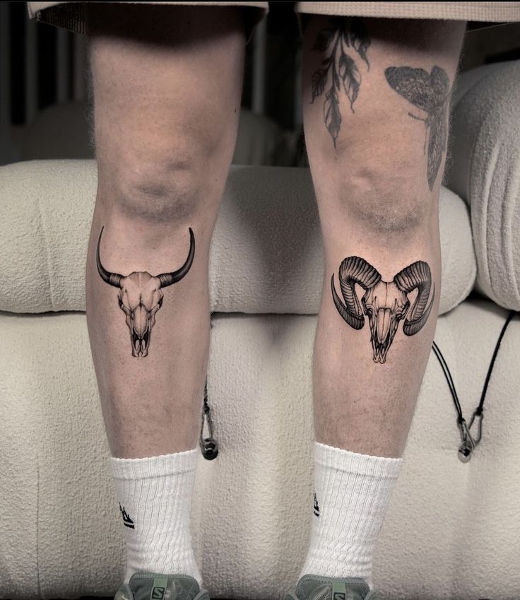 two men's legs with tattoos on them and one has an animal skull in the middle