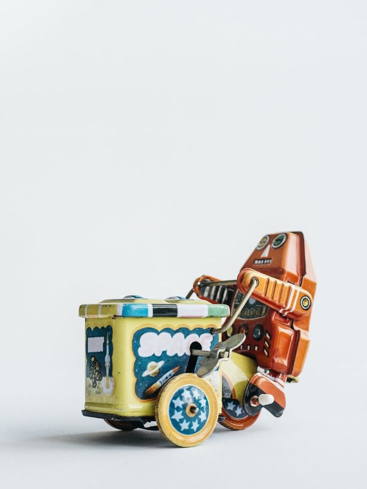 a toy truck with an orange and blue car on it's back wheels is shown in front of a white background