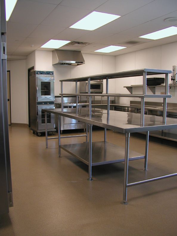 an empty commercial kitchen with stainless steel counters and ovens in the center, along with other appliances