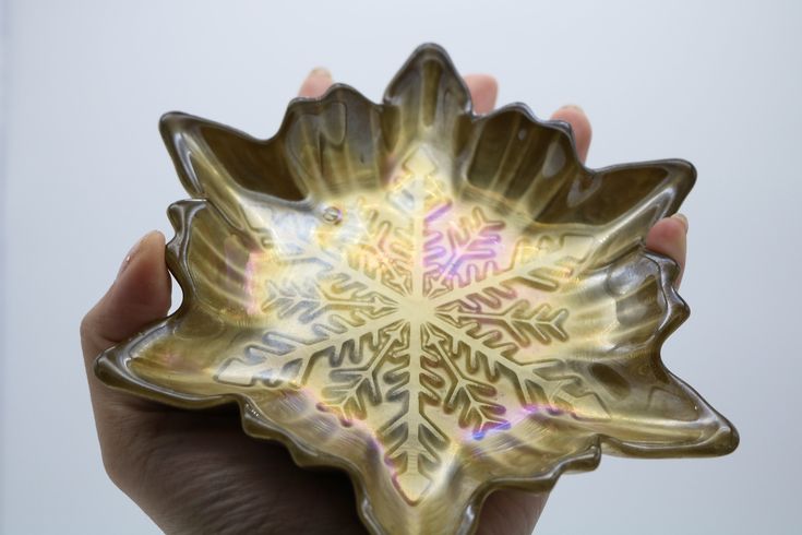 a hand holding a decorative glass bowl in it's palm