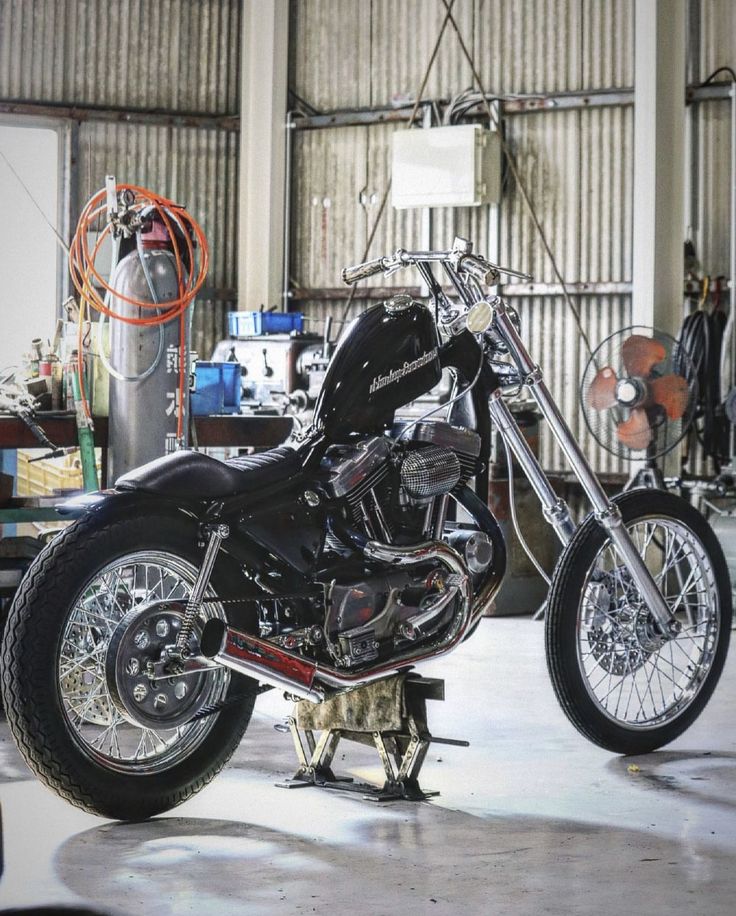 a black motorcycle parked in a garage next to a fire hydrant and other tools