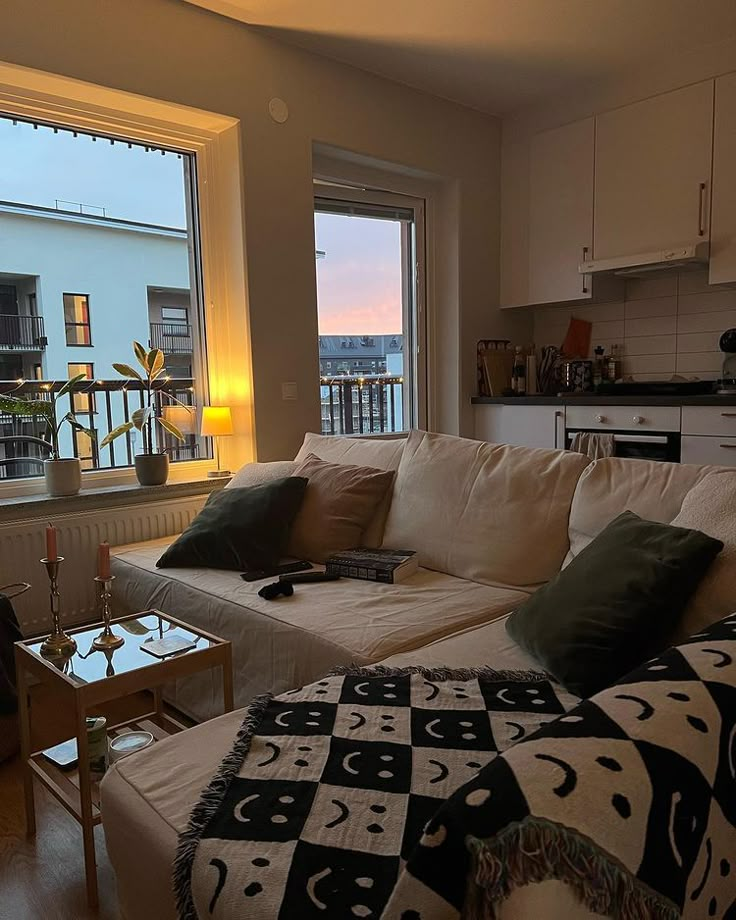 a living room filled with furniture and a large window overlooking the city at night time