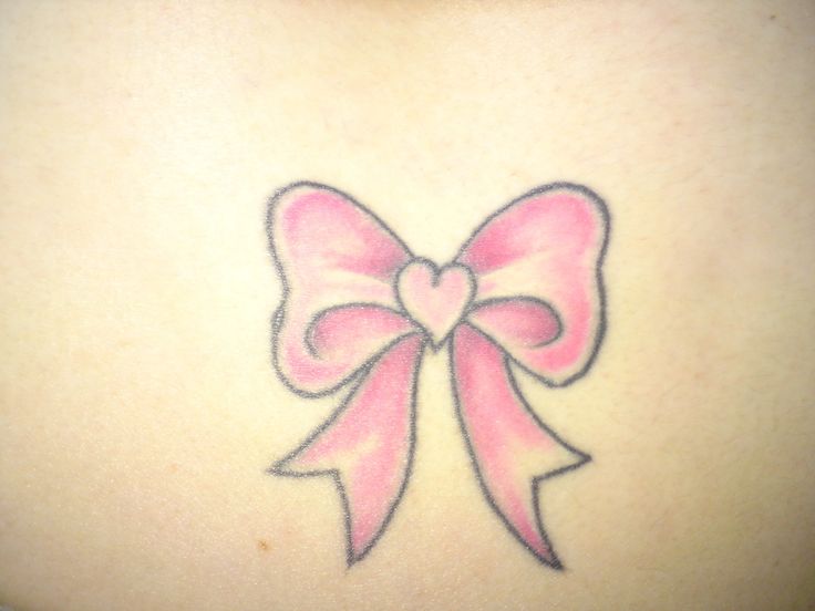 a pink bow tattoo on the back of a woman's shoulder