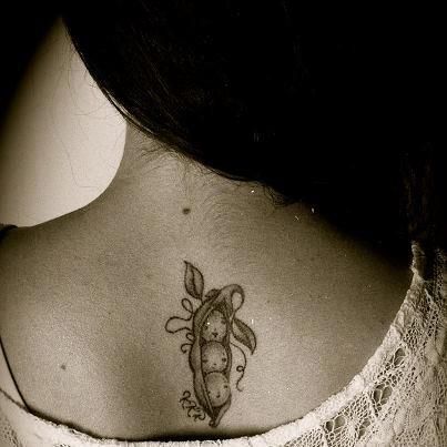 a woman with a tattoo on her back neck and shoulder is looking at the camera