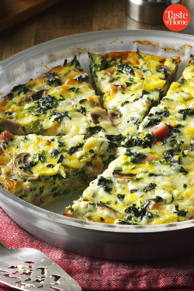 a pan filled with spinach quiche on top of a red cloth next to a knife