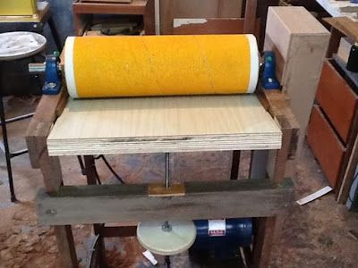 a large yellow roller sitting on top of a piece of wood in a room filled with furniture