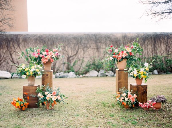 three wooden vases with flowers on them in the middle of some grass and rocks