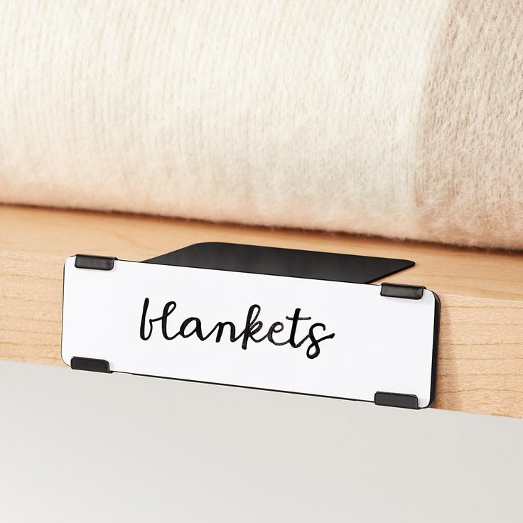 a sign that says thanks on it sitting next to a white pillow and wooden table