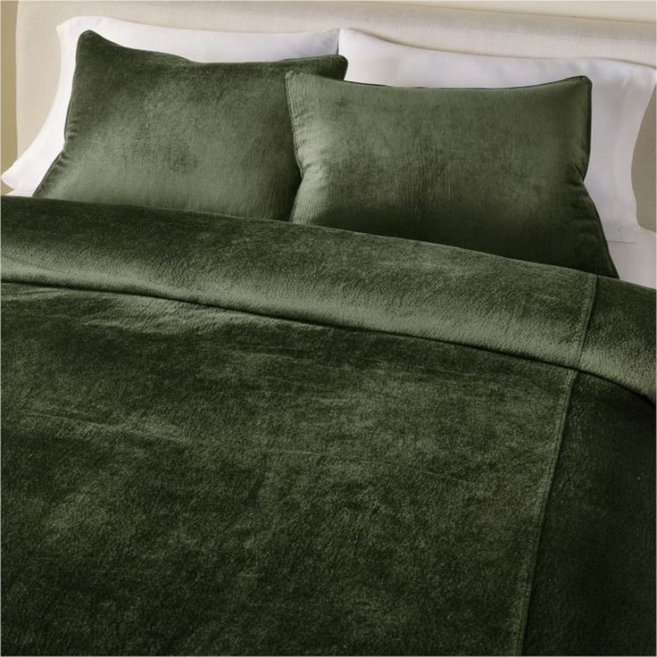 a bed with green sheets and pillows on it