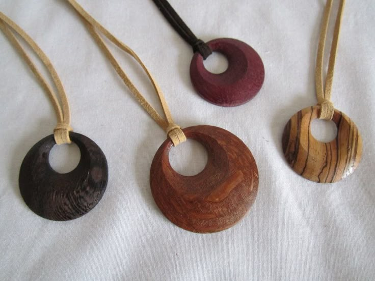 three wooden necklaces are hanging on a white cloth