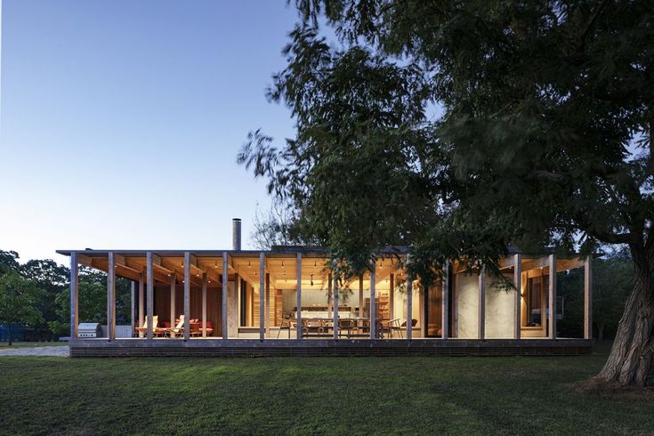 the house is surrounded by large trees and has glass walls to allow natural light into the room