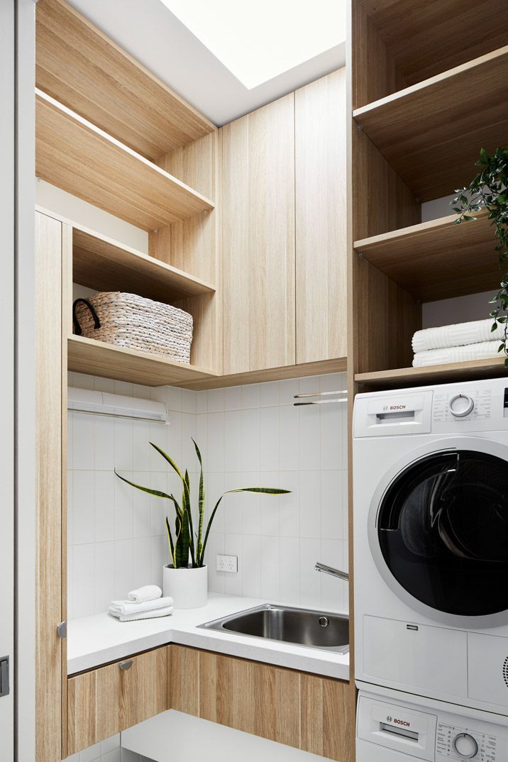 a washer and dryer in a small room with wooden shelves on the wall