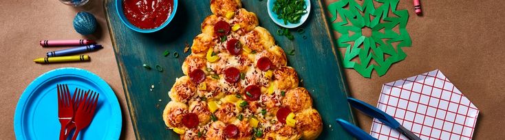 a pizza sitting on top of a green tray next to paper plates and utensils