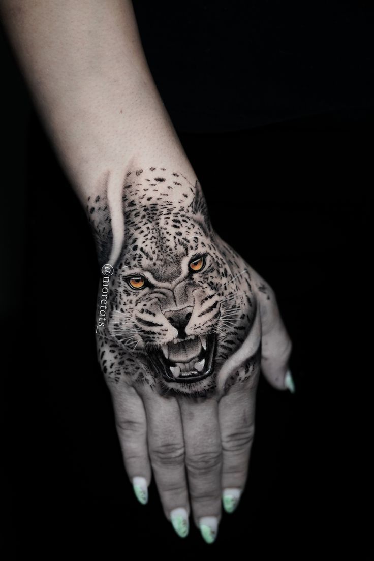 a woman's hand with a tattoo on it and a leopard face painted on the palm