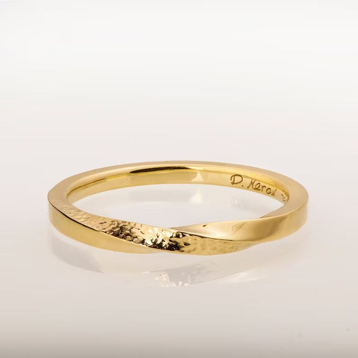 a yellow gold wedding ring on a white background