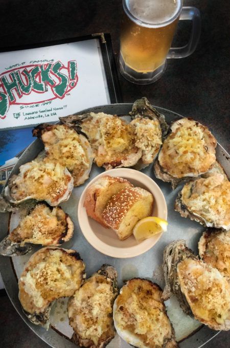 a platter filled with oysters next to a plate of bread and dipping sauce