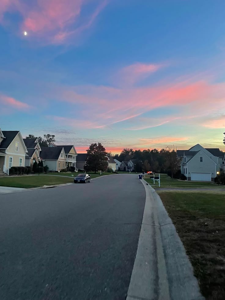 an empty street with houses in the background at sunset or dawn, as seen from across the street