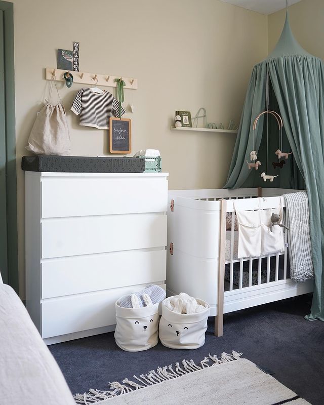 a baby's room with a crib, dresser and bed in the corner