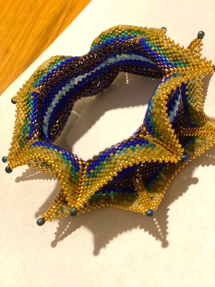 a close up of a beaded bracelet on top of a white paper with wooden table in the background