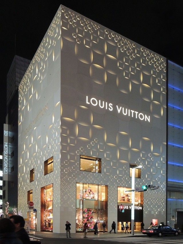 people are walking around in front of the louis vuitton store at night time