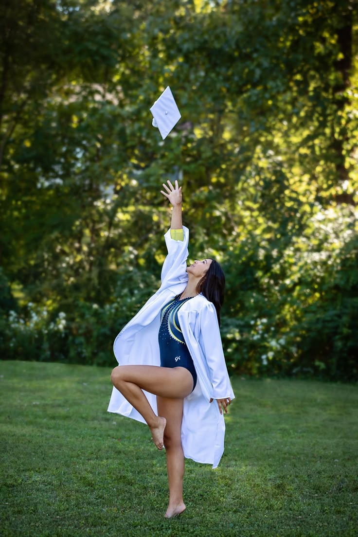 a woman in a graduation gown throwing a paper into the air with her arms and legs