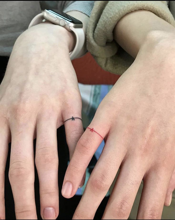 two people with rings on their fingers and one has a small cross on the middle finger