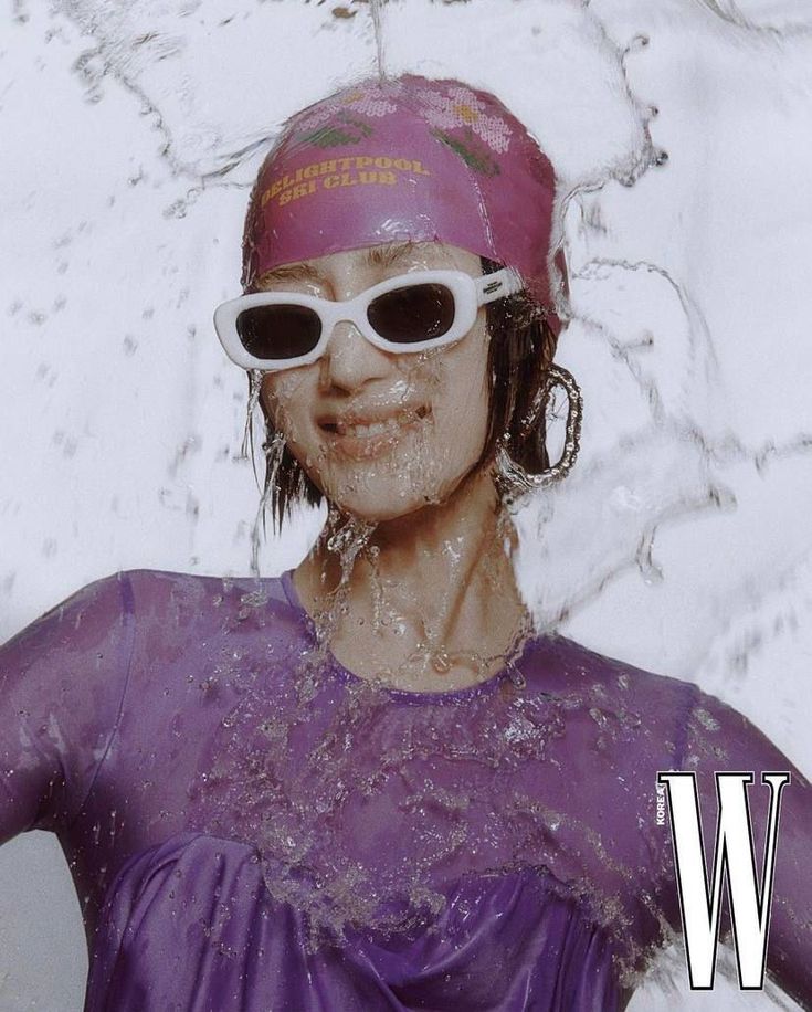 a woman wearing sunglasses and a pink hat in the snow with water splashing on her face