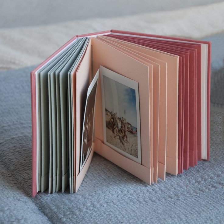 an open book with pictures on it sitting on a bed