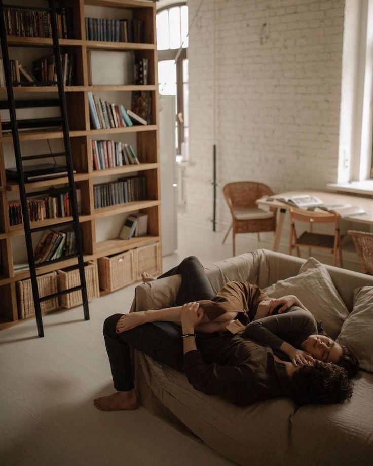 two people laying on a couch in a living room