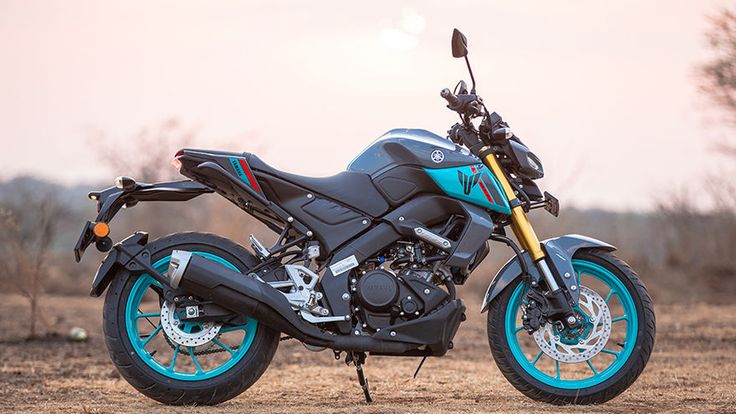 a blue and black motorcycle parked on top of a dirt field