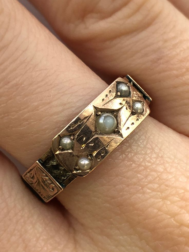 A Victorian 9ct gold pearl mourning ring. This ring is Hallmarked Chester, with the date mark of 1888. The largest pearl is set at the centre of the ring, and measures 3 x 3mm's. Set in to each corner of the central section are four round seed pearls which each measure 2 x 2mm's. The centre piece takes the form of a buckle, and around the ring there are detailed gold belt loops. Beneath the loops there is a ring of fine hair that has been very carefully and delicately platted. An excellent and meaningful example of Victorian sentiment. Finger size Q and a half. Unfortunately we are unable to re-size this ring. Unique Vintage Jewelry, Statement Gold Rings, 1800s Engagement Ring, 1920s Rings, Edwardian Rings, 1800s Jewelry, Antique Gold Ring, Victorian Style Rings, Victorian Jewellery