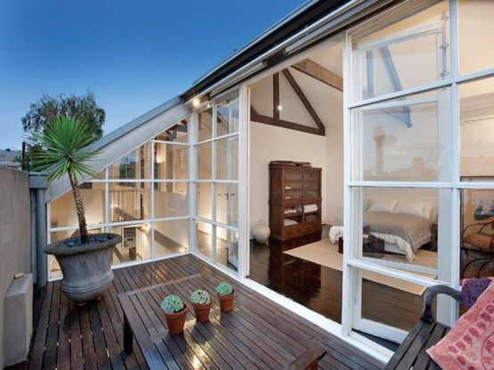 an outdoor deck with chairs and potted plants next to the sliding glass doors that open up onto a patio area