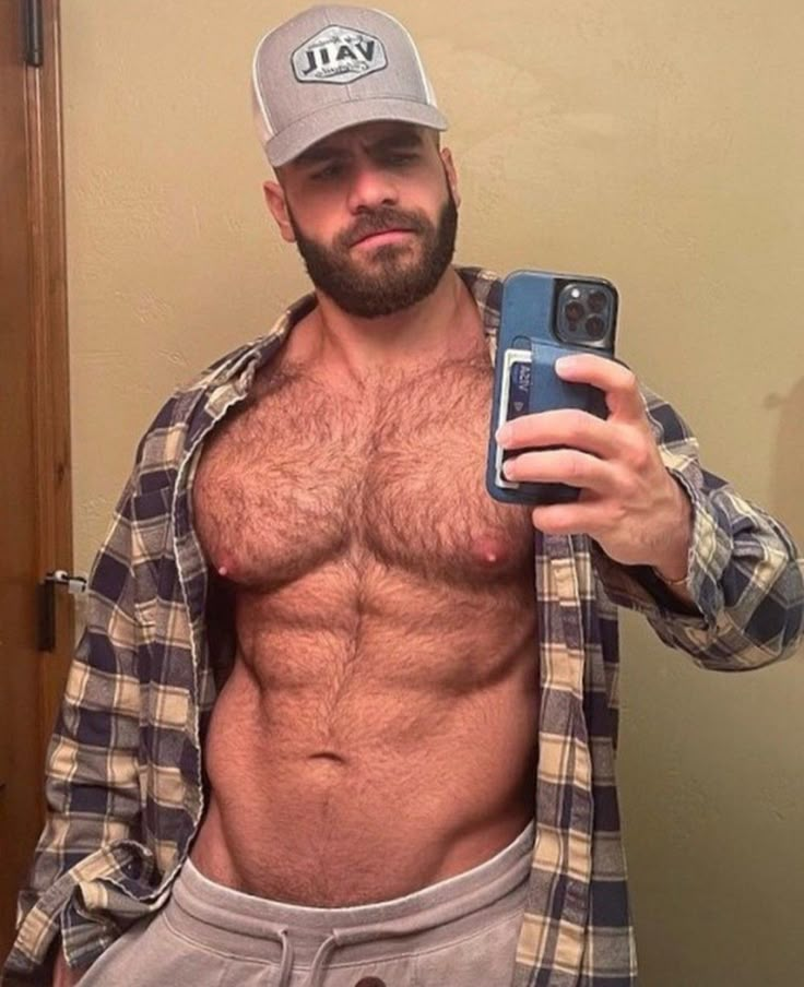 a shirtless man taking a selfie in the bathroom with his cell phone and towel