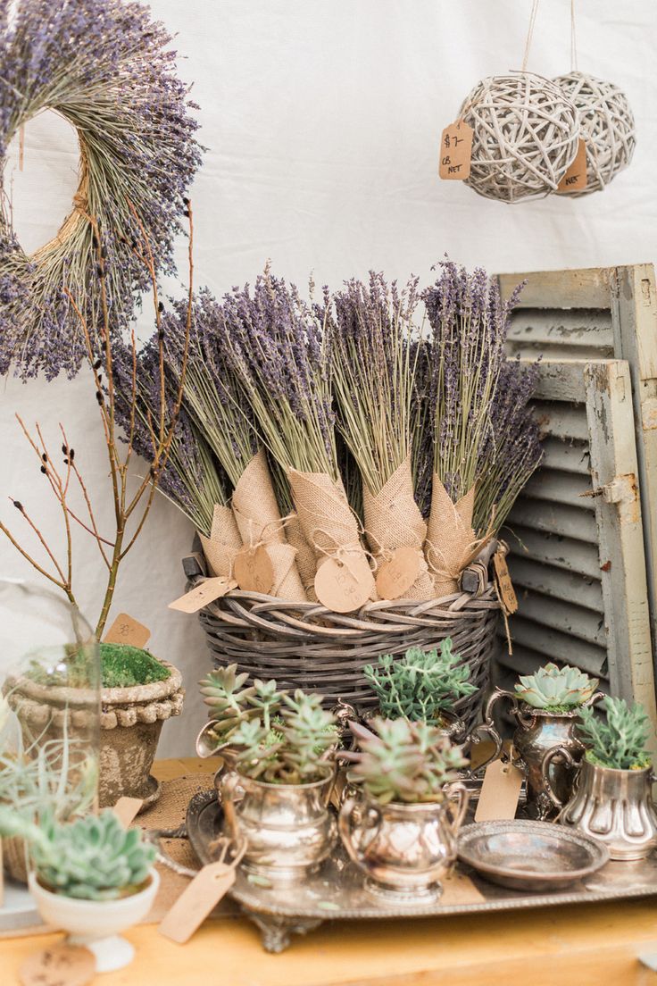 lavenders and succulents are arranged in baskets on a table