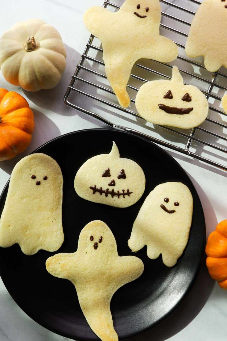 halloween pancakes on a plate with ghost faces and pumpkins in the background