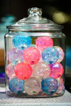 a glass jar filled with lots of different colored balls