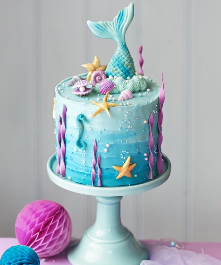 a cake decorated with blue icing and mermaid decorations