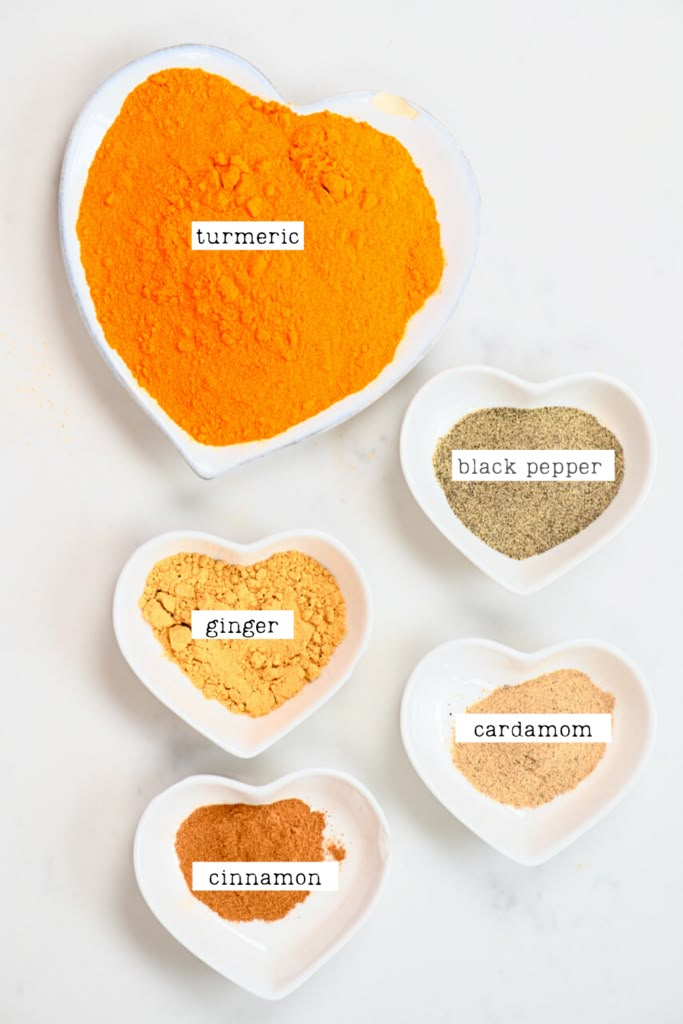 four bowls filled with different types of spices on top of a white table next to each other