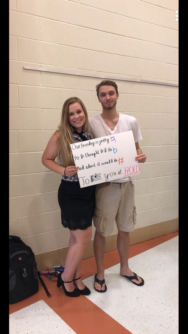 two people standing next to each other holding a sign