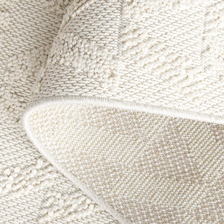 the texture of an upholstered blanket is shown in white and neutral colors, as seen from above