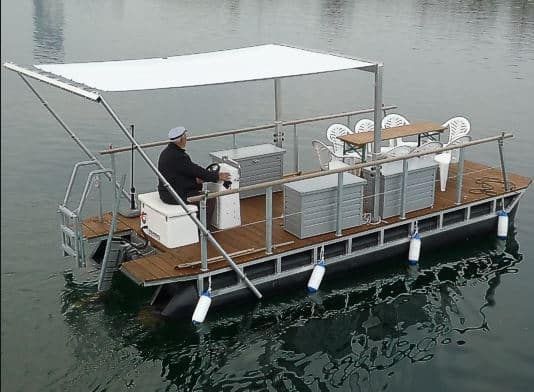 a man sitting on top of a boat in the water next to an awning