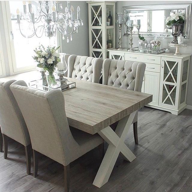 a dining room table with chairs and a chandelier in the back drop off