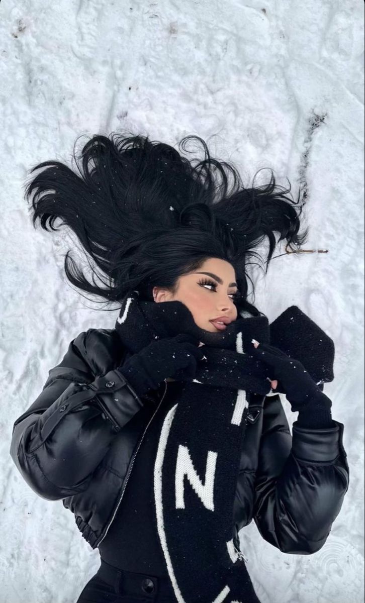 a woman with long black hair is posing in the snow