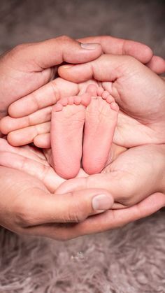 two hands holding a baby's feet in the palm of another person's hand