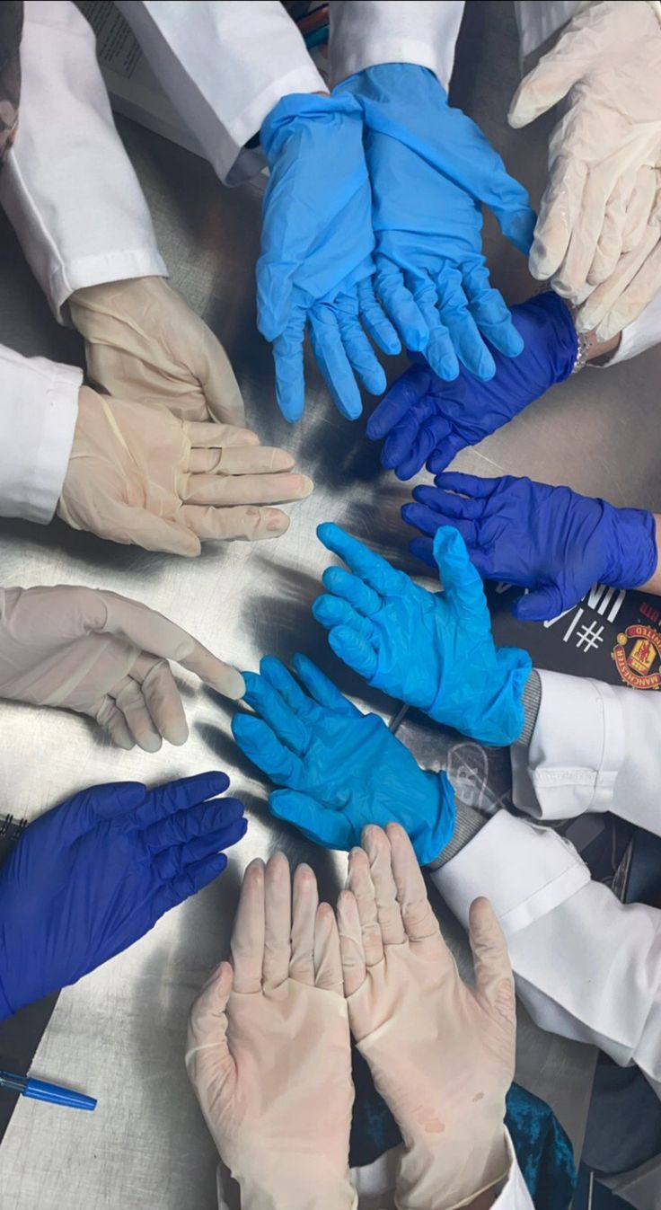 many hands in blue and white gloves are arranged in a circle