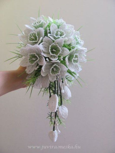 a bridal bouquet with white flowers and greenery is held in someone's hand