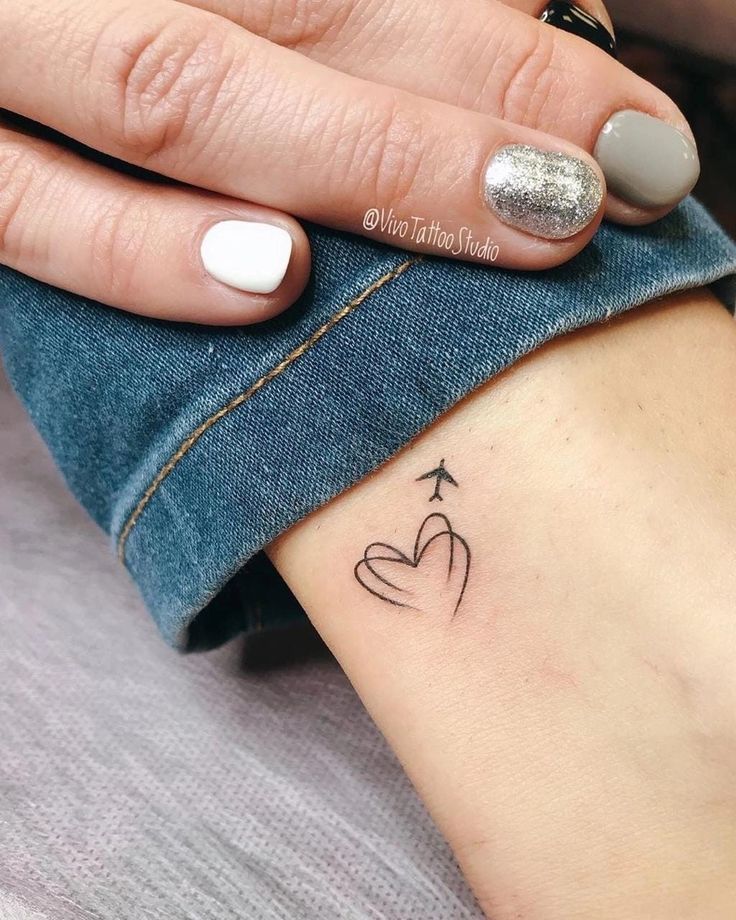 a woman's left arm with a small tattoo on the wrist and an arrow