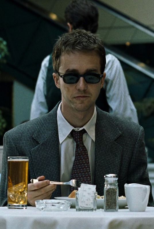 a man sitting at a table with food and drinks in front of him, wearing sunglasses